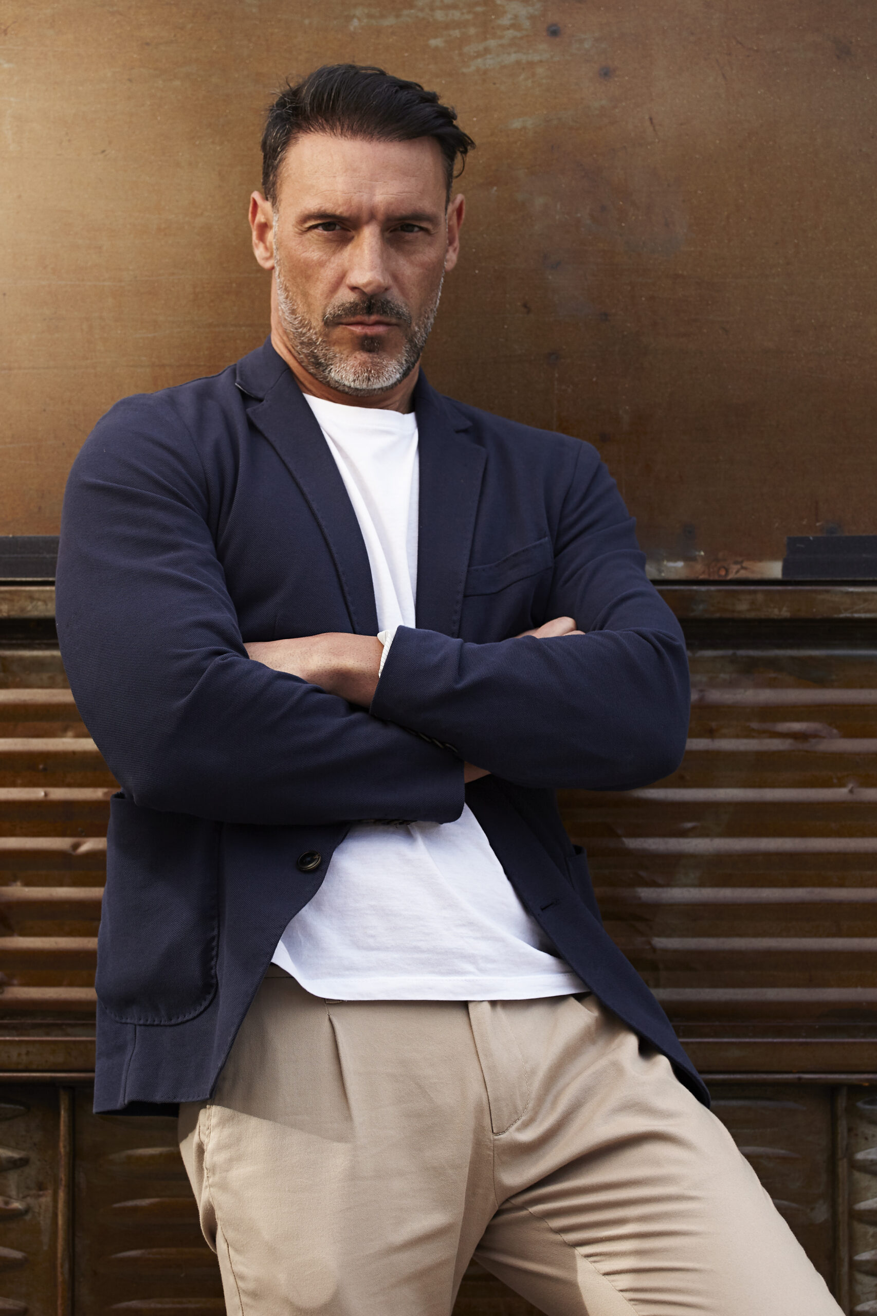 middle-aged-man-wearing-leaning-against-rusty-colored-background